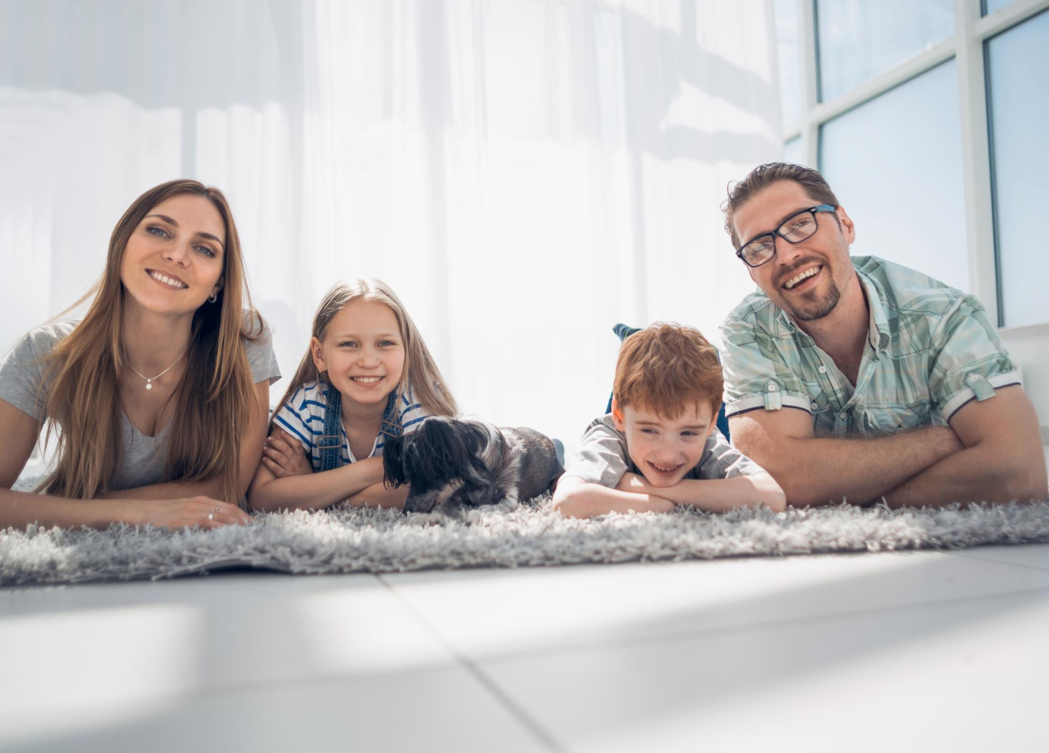 eine glückliche Familie die auf dem Boden liegt und lacht.