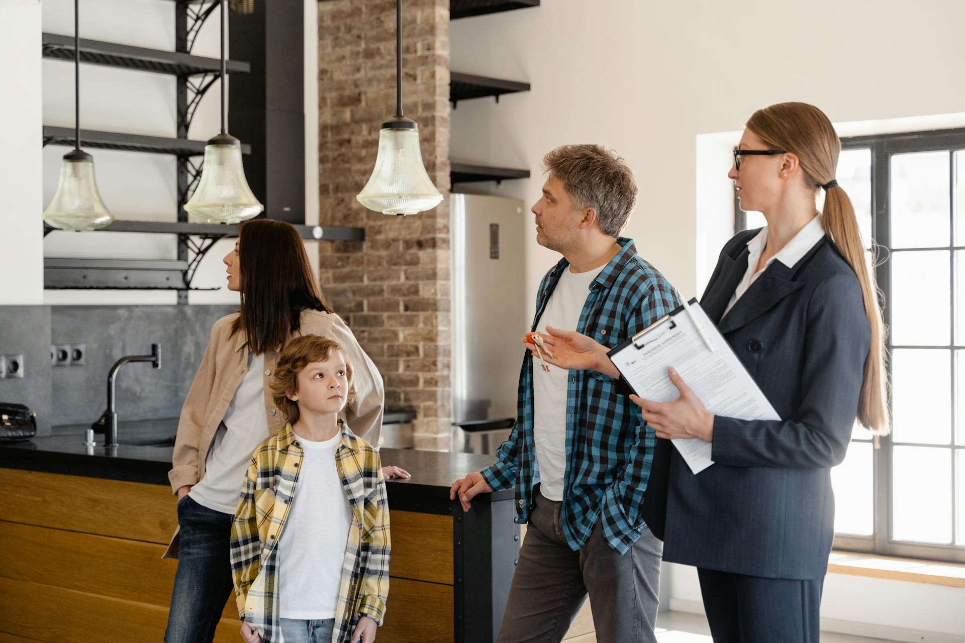 Immobilienmaklerin führt eine Familie durch eine moderne Küche und erklärt Details zur Immobilie während einer Besichtigung.